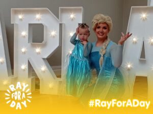 Little girl in a princess dress poses for a picture with woman dressed as Princess Elsa