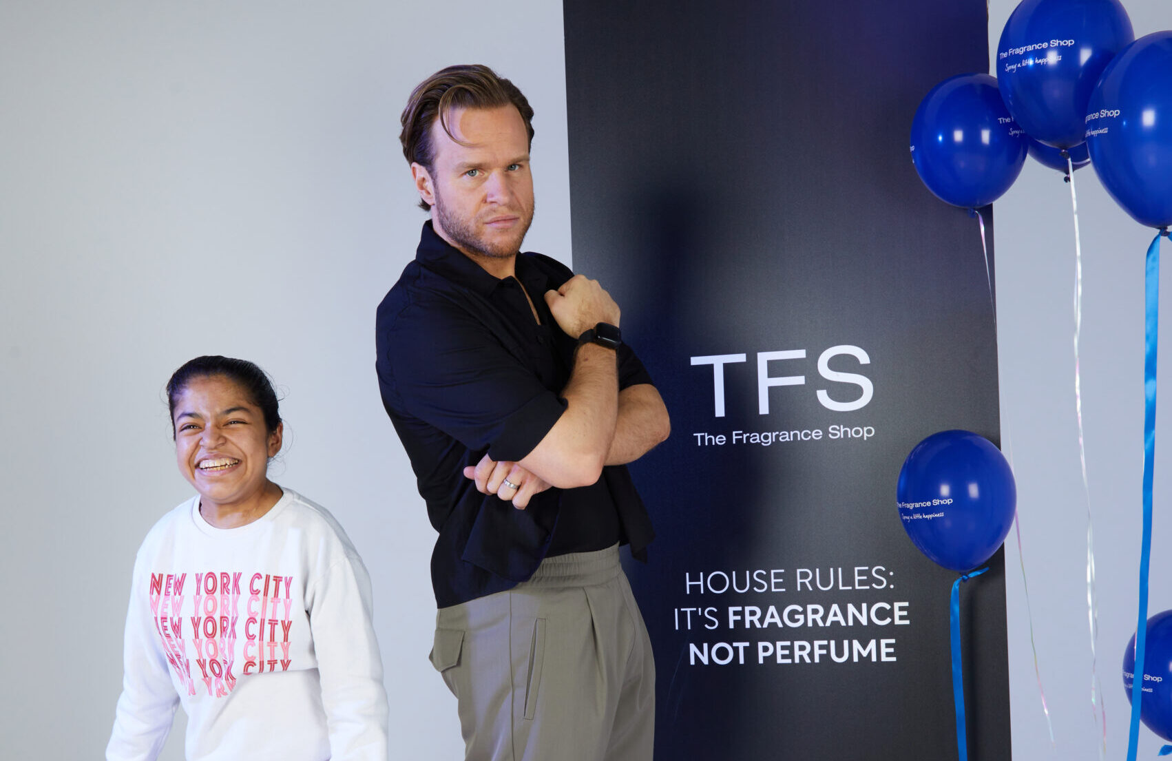 Young teen girl poses with man. They are in a white wall-ed photography studio