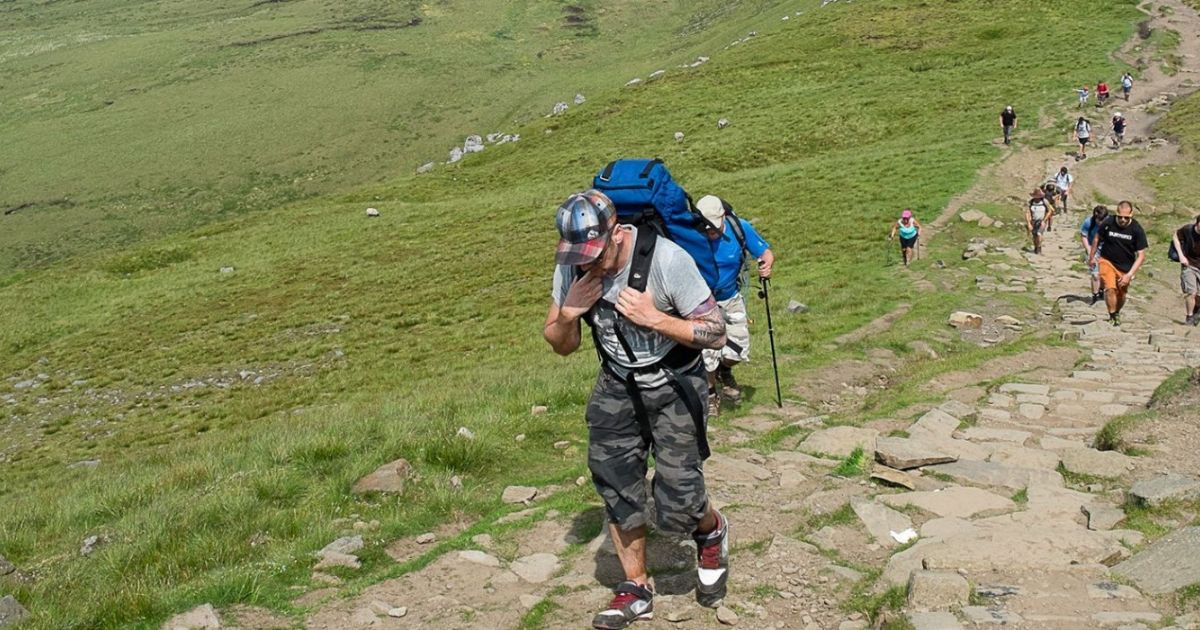A variety of people treking down a peak.