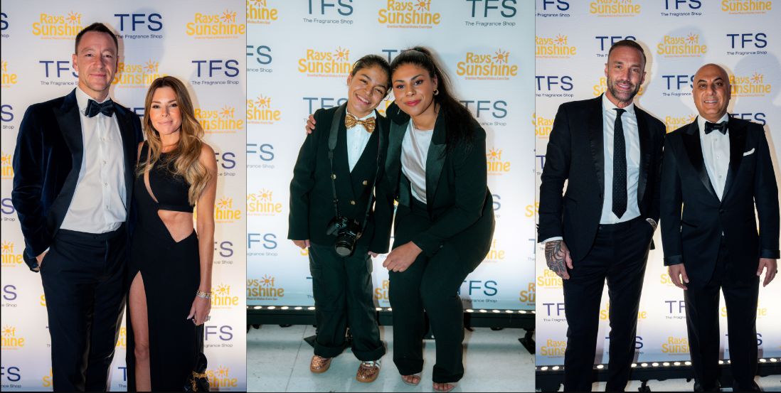 Group of people in black tie outfits smile for a group pic in front of a step and repeat board