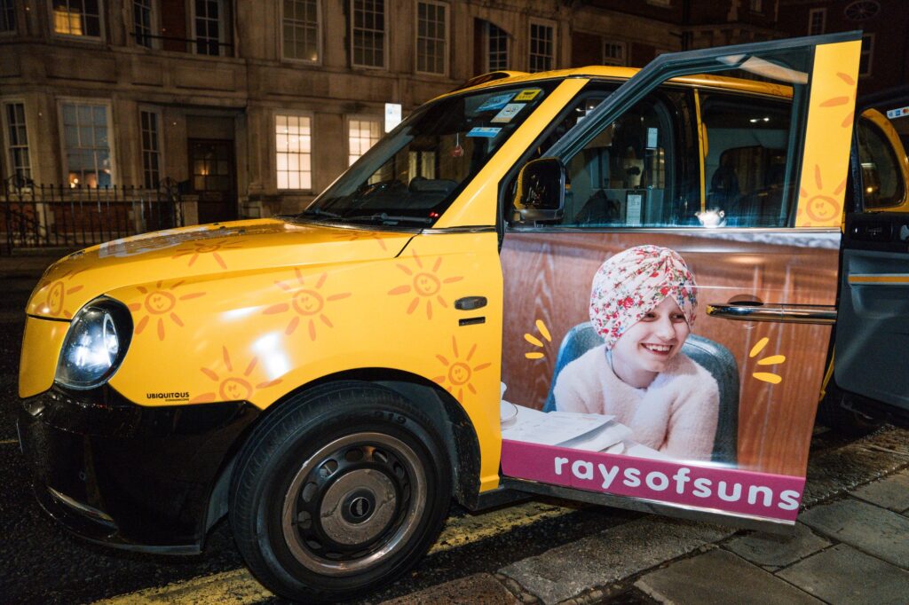 Bright yellow taxi with face of a little girl on its front door.