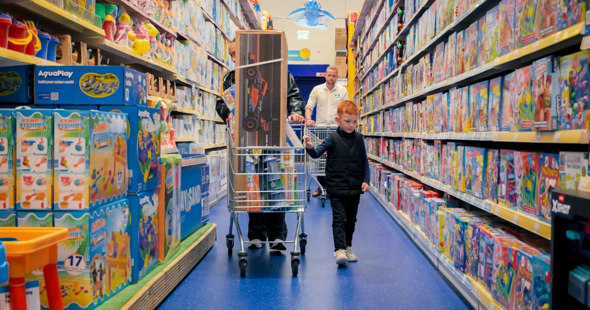 A person and child pushing a cart in a toy store