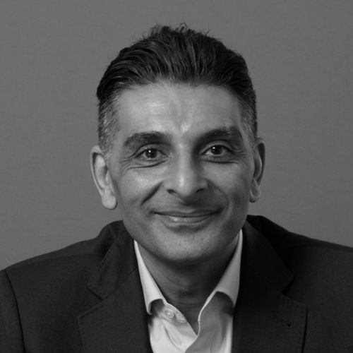 Divyesh headshot in black and white. He has black hair. He is wearing a business suit with no tie.