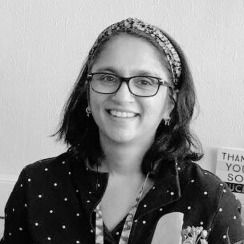 Headshot in black and white of Dr Ronelle Naidoo she has long black hair and is wearing glasses