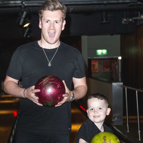 Oli White holding a bowling ball with a small boy also holding a ball