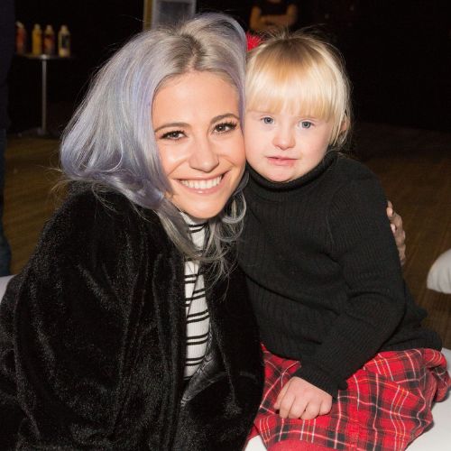 Pixie Lott smiling to camera hugging a little girl with blonde hair