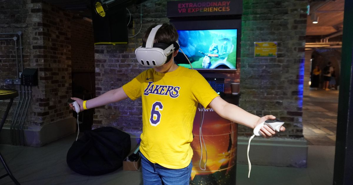 A young boy wearing a yellow shirt using a VR headset