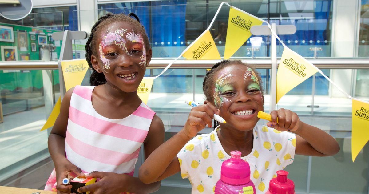 A couple of young girls with face paint on smiling at camera