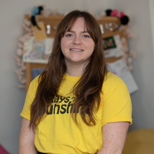 Zoe wearing the Rays of Sunshine yellow t-shirt. She is standing. Zoe has brown hair.