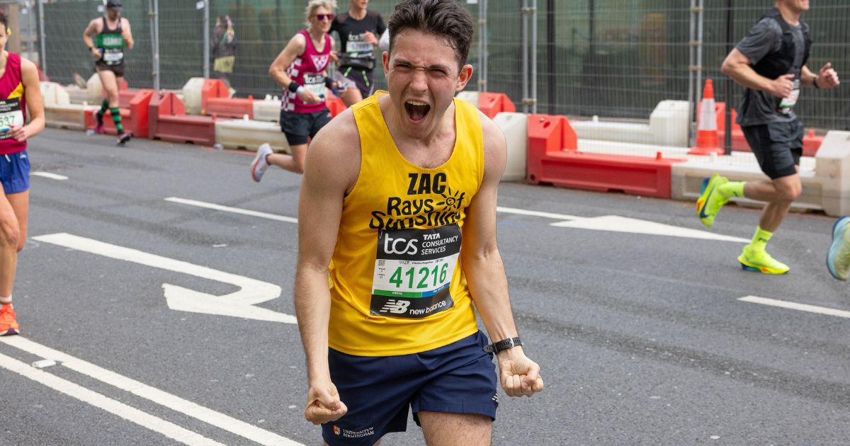 A London Marathon runner in a yellow Rays of Sunshine vest cheering the crowd