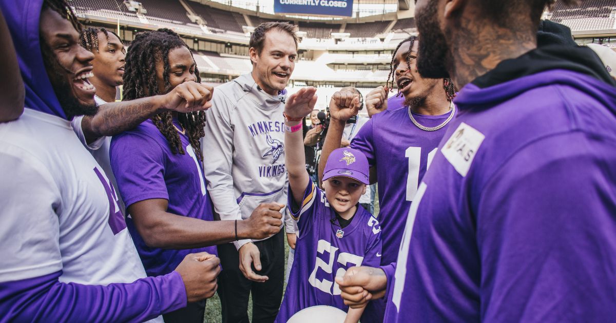 A young boy with his arm in the air in a middle of a huddle of american football players