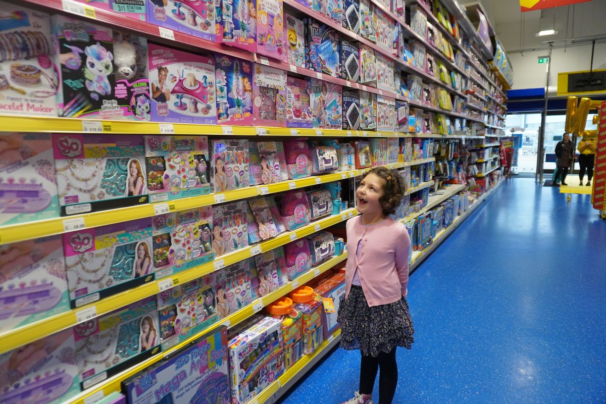 Little girl gazes up in amazement while stood in the aisle of a toy shop