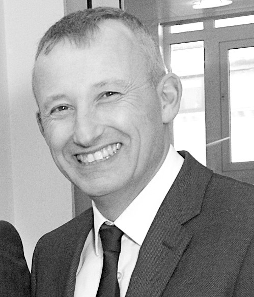 Justin Randall headshot smiling to camera in black and white