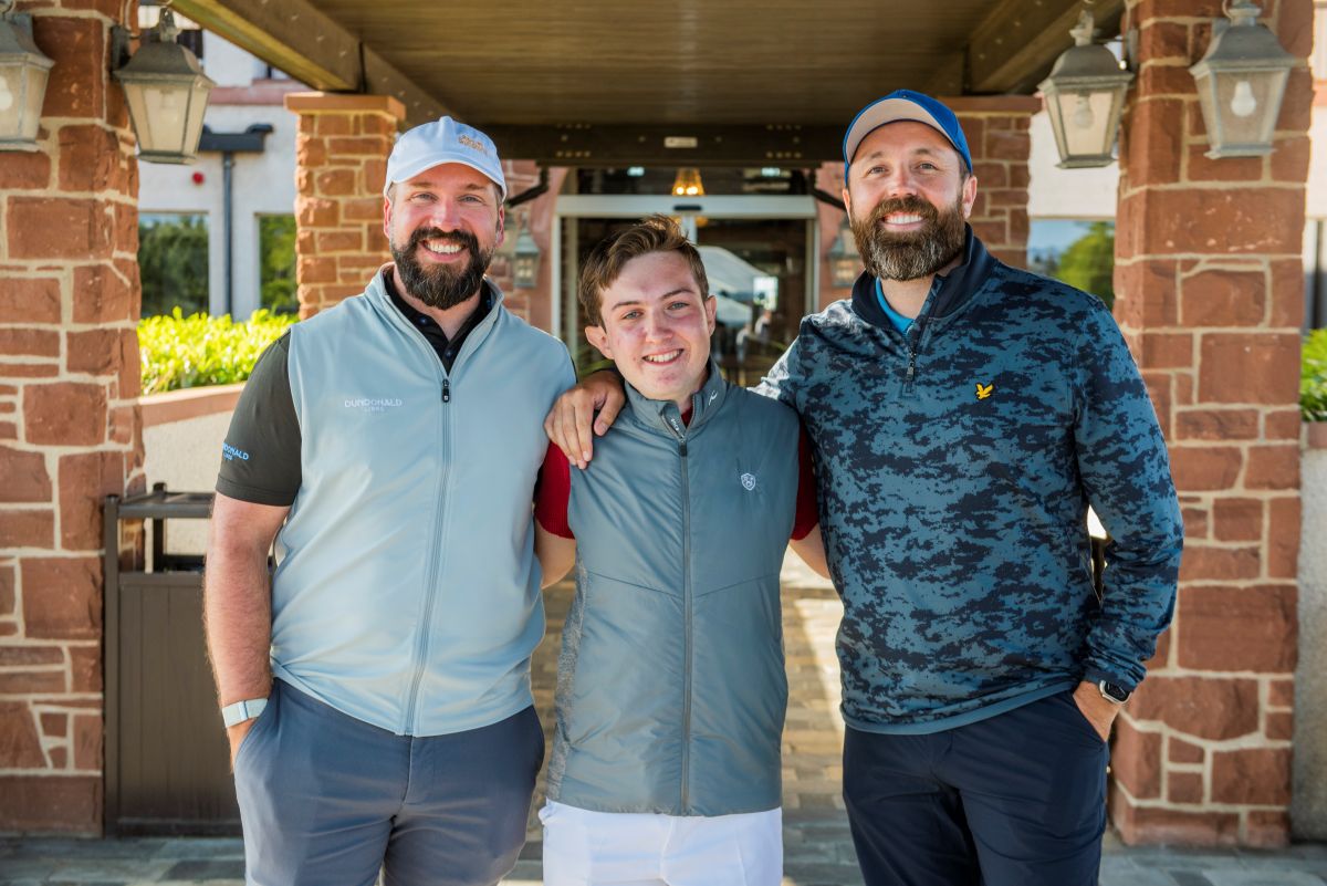 Teen boy poses for a picture with two bearded men