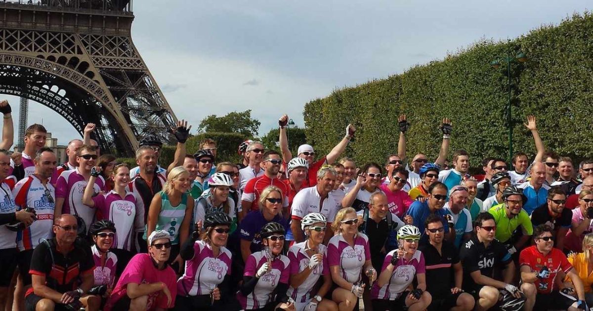 A group of cyclists in front of the Eiffel Tower posing.