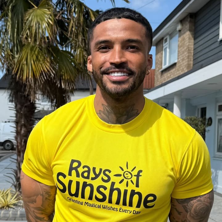 Man smiling for the camera, while wearing a yellow Rays of Sunshine t-shirt