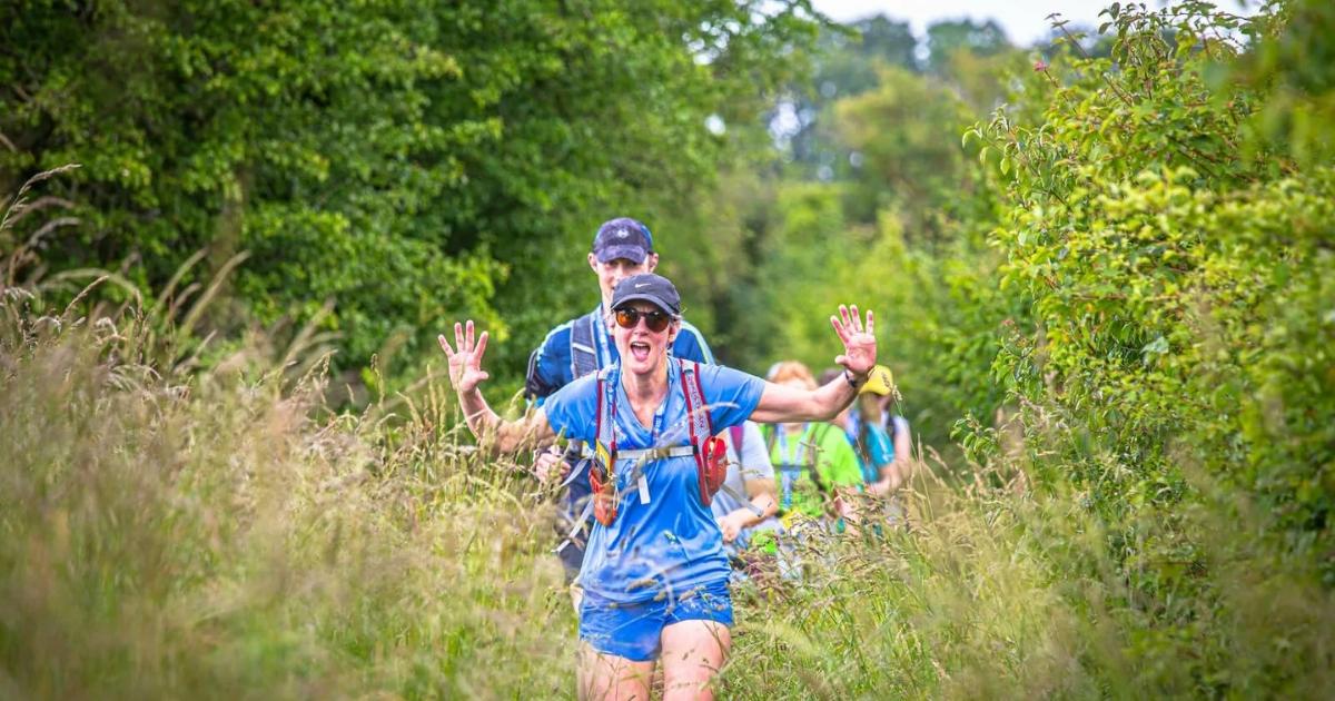 women with hands up excitedly running through long grass