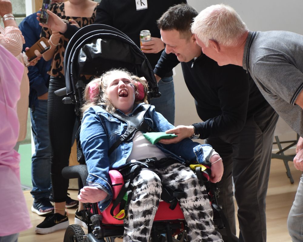 Girl in wheelchair being smiled at by family members