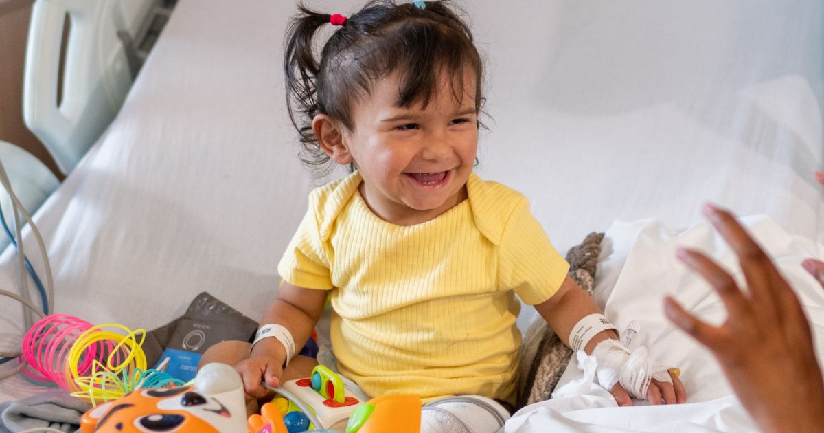 Little girl in hospital bed laughing at someone off camera