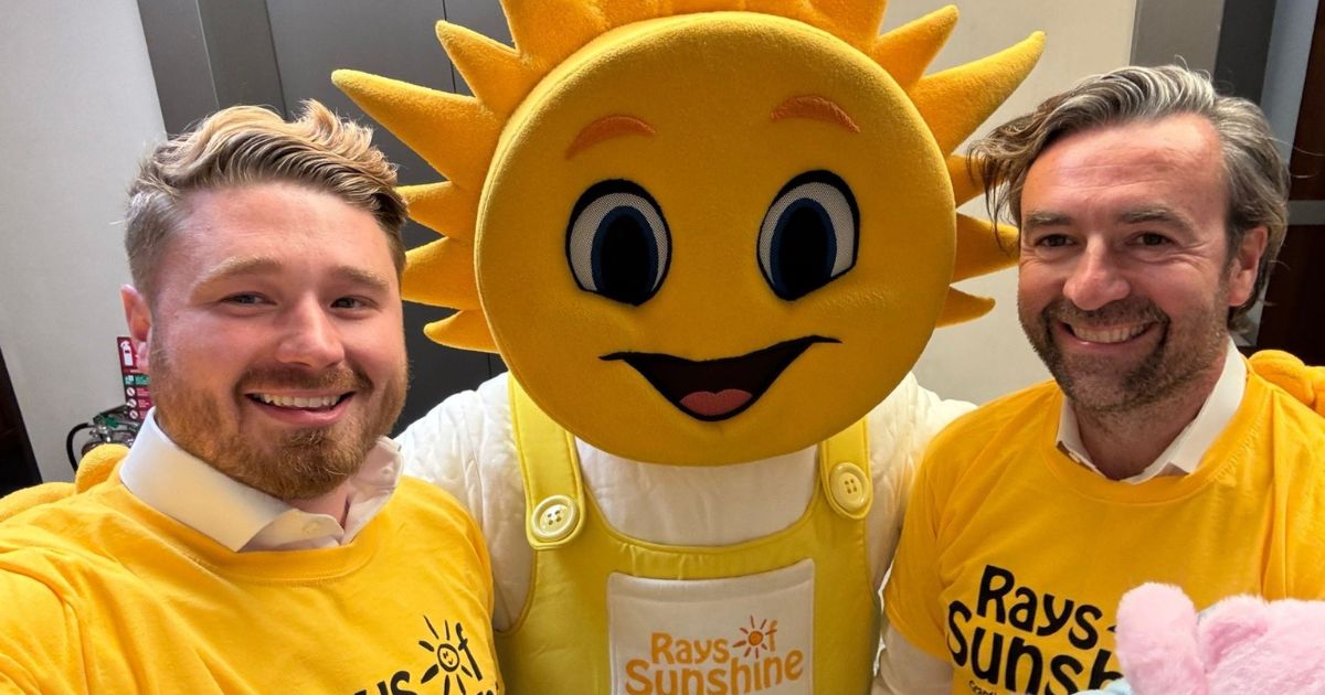 Two volunteers taking a selfie with Sunny the mascot