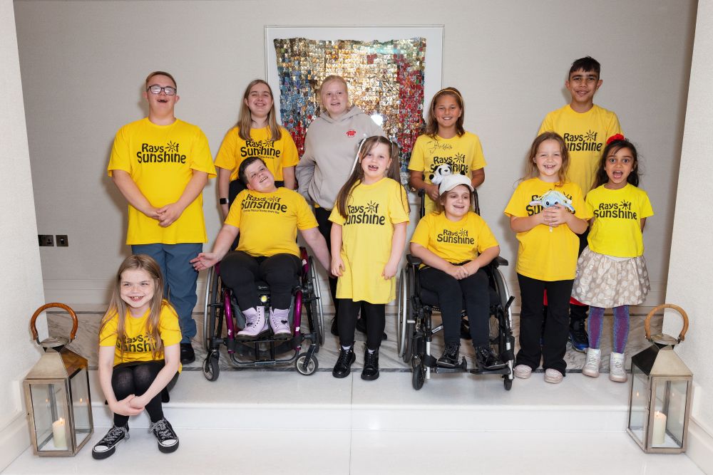 Diverse group of children and young people pose for a picture in yellow Rays of Sunshine t-shirts
