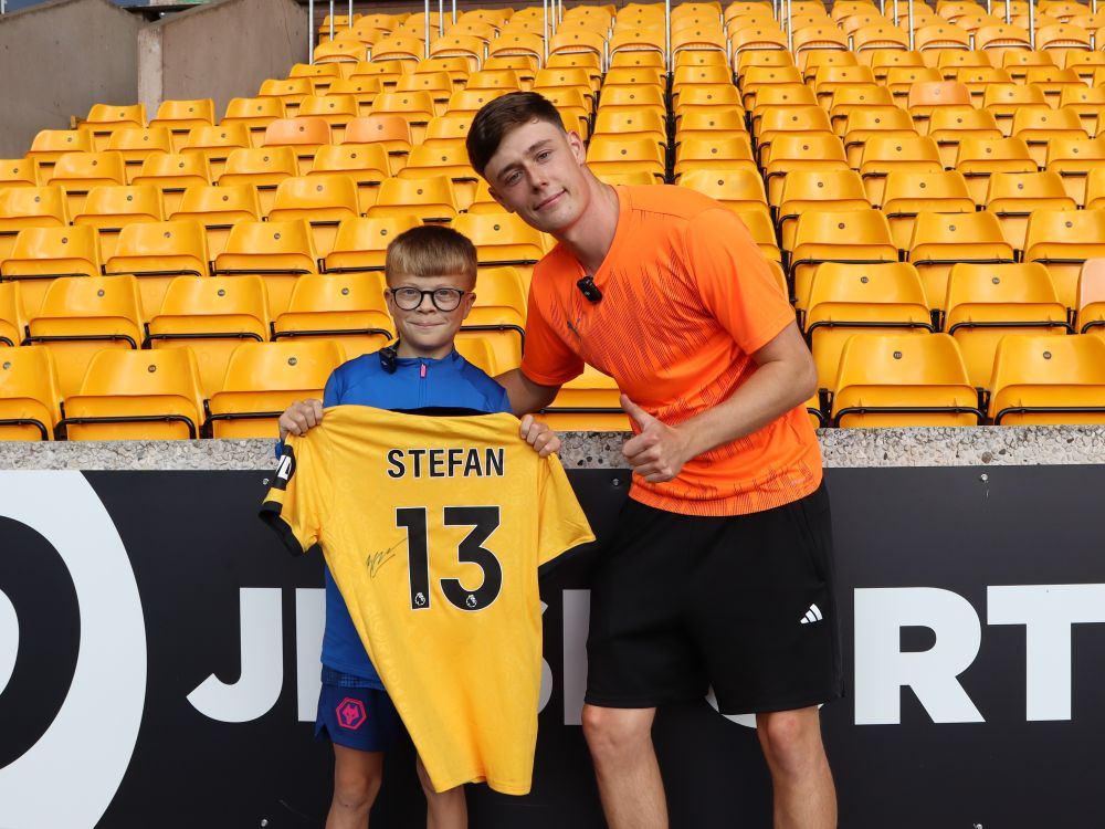 Ten boy and young man smile for a picture, while the young one holds up a yellow football shirt with Stfan 13 on the back