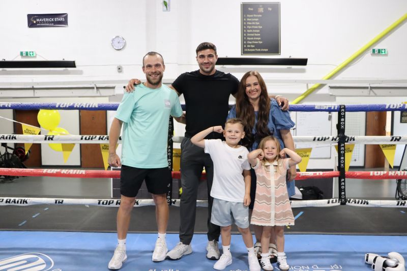 Family of four stands with Tommy Fury while in the boxing ring of a gym