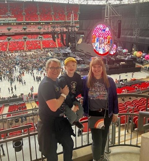 Parents and young son smile for a picture with Wembley stadium in the background