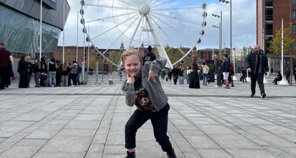 Otis smiling and posing for picture in front of a ferris wheel