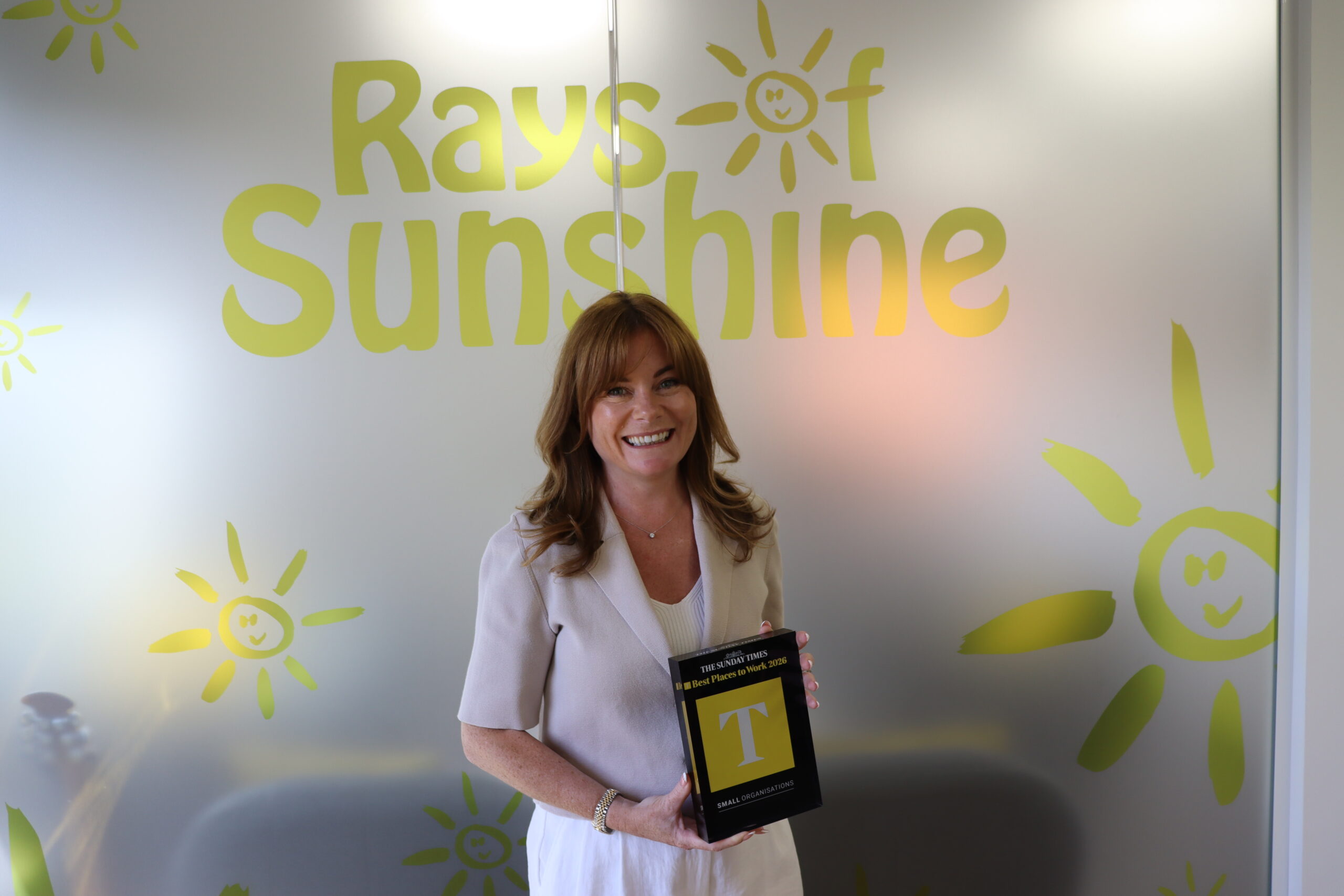 CEO Amy Chambers holds the award and is smiling toward the camera