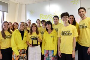 group of people in yellow tshirts pose for a picture while celebrating a new award