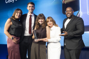 Group of people onstage at Third Sector Awards smiling to camera with award